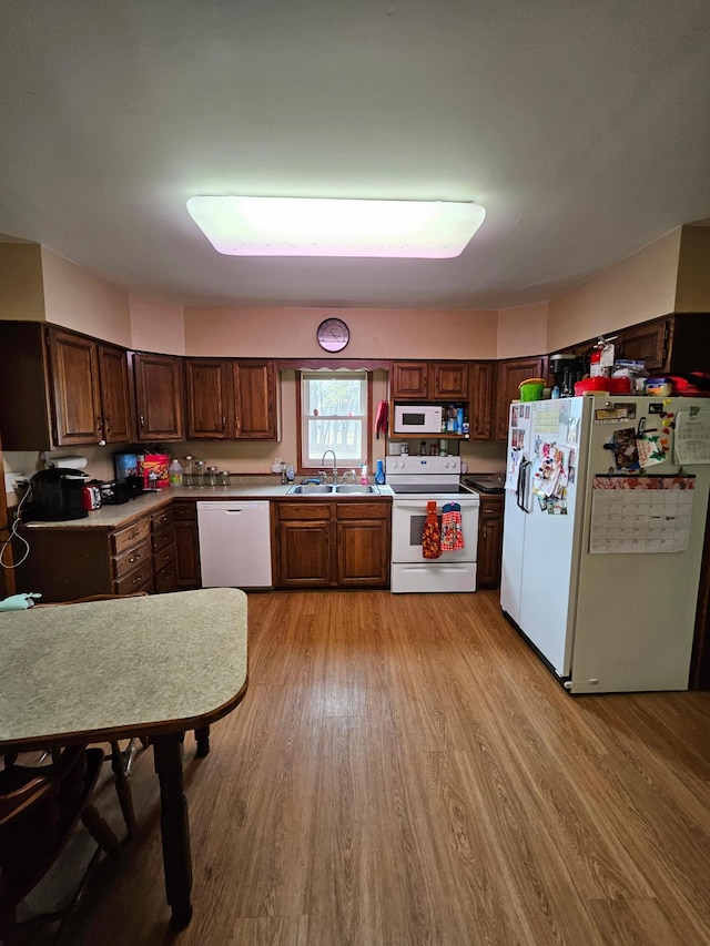 kitchen with white appliances, light wood-style flooring, light countertops, and a sink