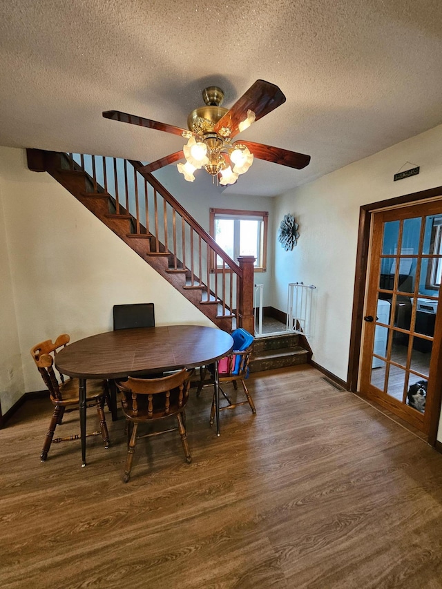 dining room with stairway, a textured ceiling, baseboards, and wood finished floors