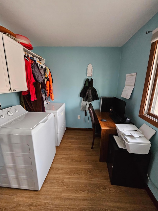 washroom featuring baseboards, cabinet space, separate washer and dryer, and wood finished floors