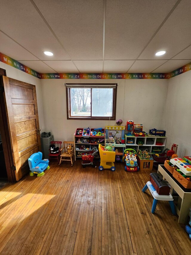 playroom with hardwood / wood-style floors and a paneled ceiling