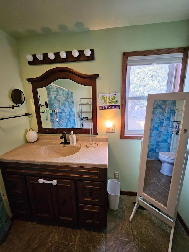 full bathroom with toilet, vanity, and baseboards