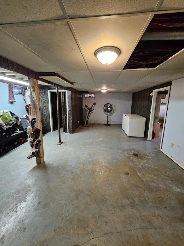 finished basement with refrigerator and a paneled ceiling