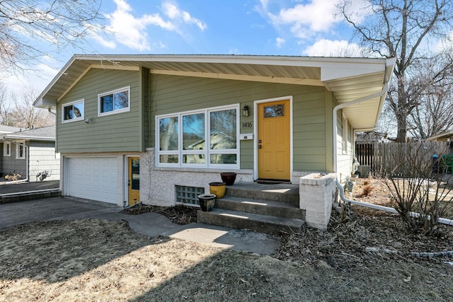 view of front of home with entry steps, concrete driveway, a garage, and fence