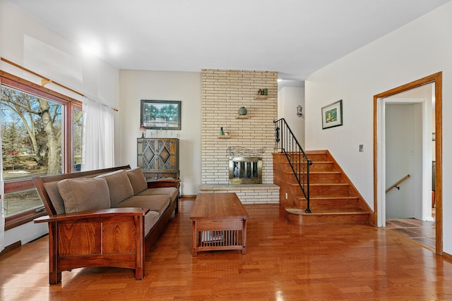 living room with a fireplace, stairs, and wood finished floors