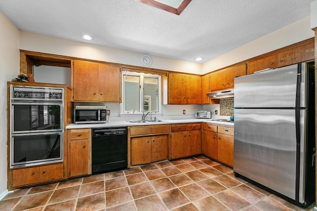 kitchen featuring brown cabinets, black appliances, under cabinet range hood, a sink, and light countertops