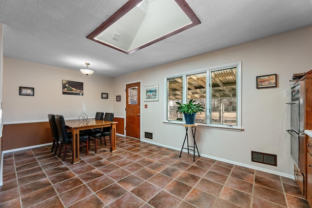 dining room featuring dark tile patterned floors, visible vents, and a textured ceiling