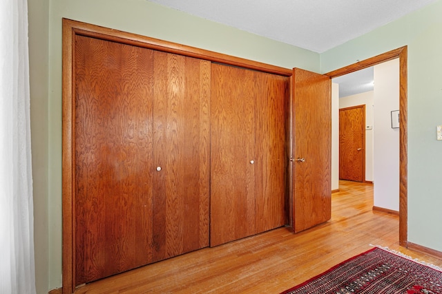 unfurnished bedroom featuring a closet, baseboards, and light wood finished floors