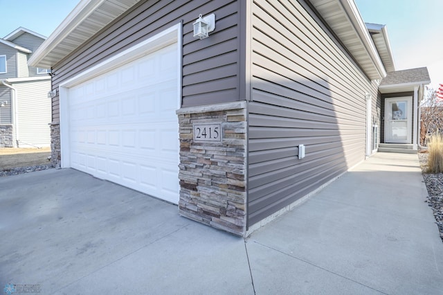 view of home's exterior with a garage, stone siding, and concrete driveway