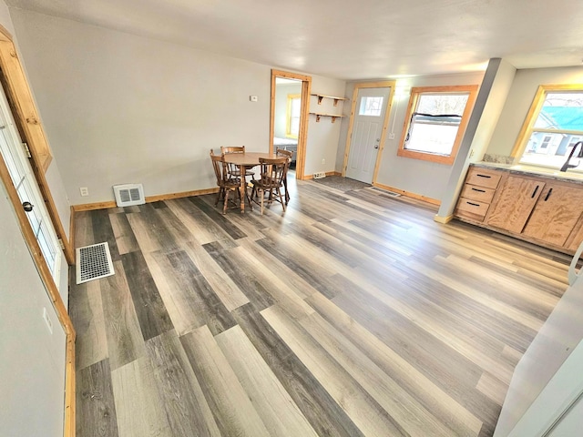 foyer with light wood finished floors, visible vents, and baseboards