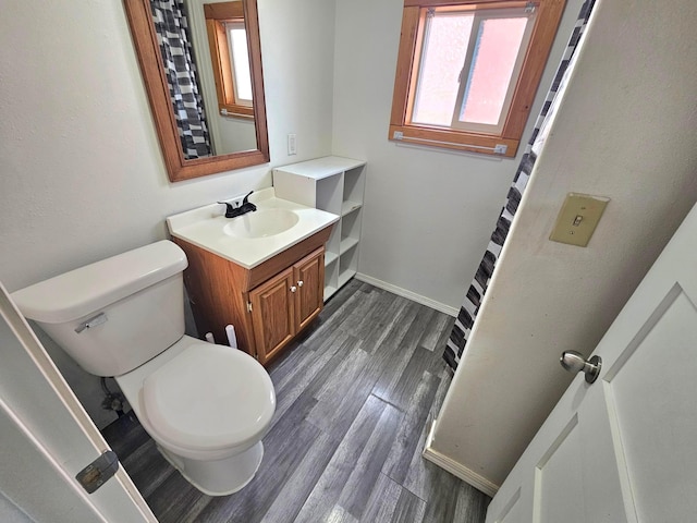 bathroom with vanity, toilet, wood finished floors, and baseboards