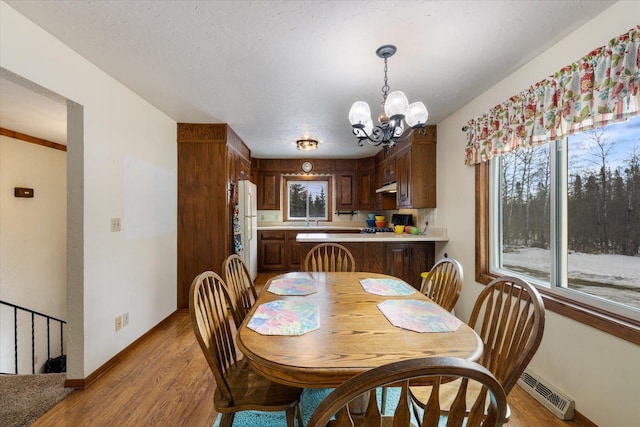 dining room with light wood-type flooring, visible vents, baseboards, and a chandelier