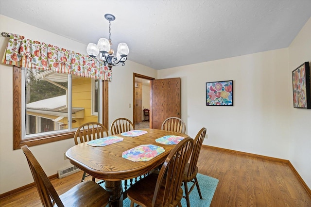 dining area with visible vents, baseboards, a notable chandelier, and wood finished floors