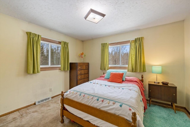 bedroom featuring visible vents, carpet flooring, a textured ceiling, and baseboards