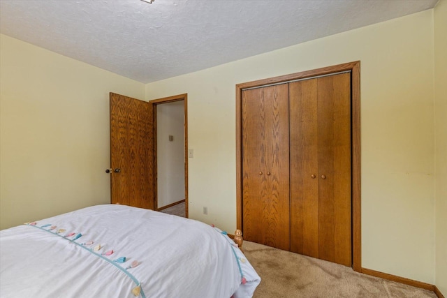 carpeted bedroom featuring a closet, baseboards, and a textured ceiling