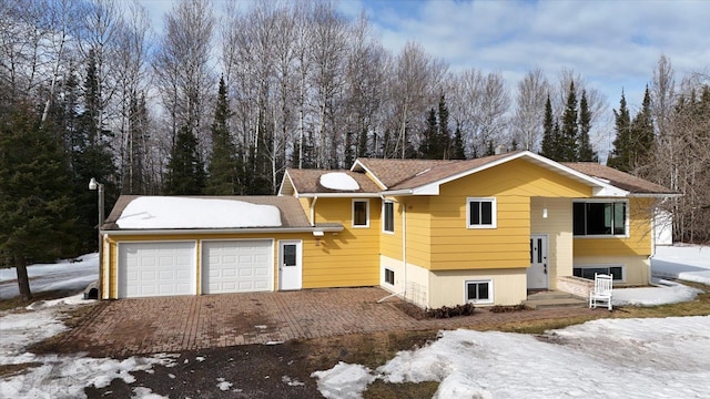 raised ranch featuring an attached garage and driveway