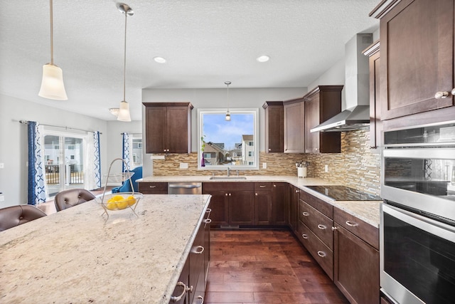 kitchen featuring a sink, stainless steel appliances, wall chimney range hood, decorative backsplash, and dark wood-style flooring