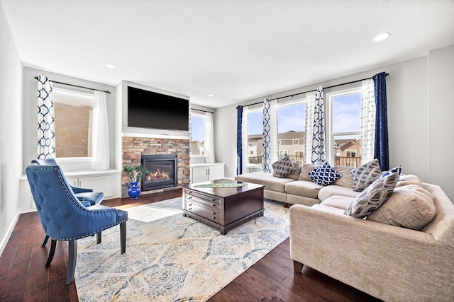 living area with recessed lighting, a textured ceiling, a stone fireplace, and hardwood / wood-style floors