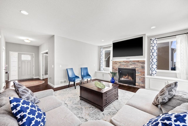 living room featuring visible vents, a fireplace, baseboards, and wood finished floors