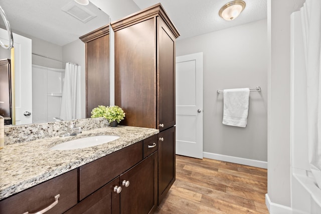 bathroom featuring vanity, wood finished floors, visible vents, baseboards, and a textured ceiling