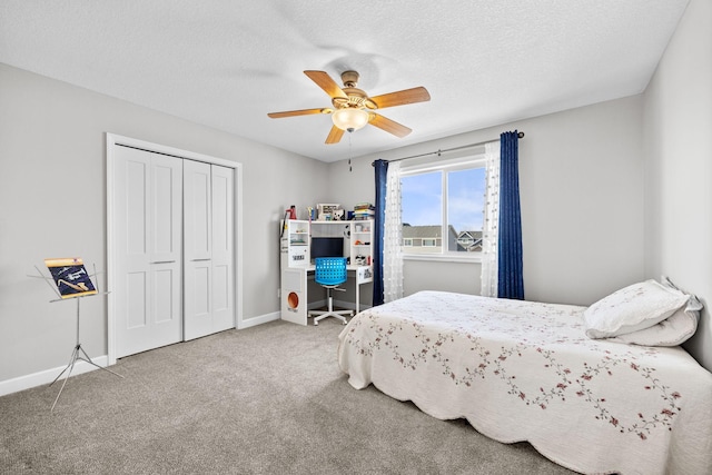 carpeted bedroom featuring a closet, a textured ceiling, baseboards, and a ceiling fan