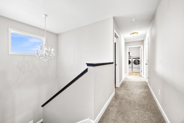 corridor with an upstairs landing, washer and dryer, carpet floors, an inviting chandelier, and baseboards