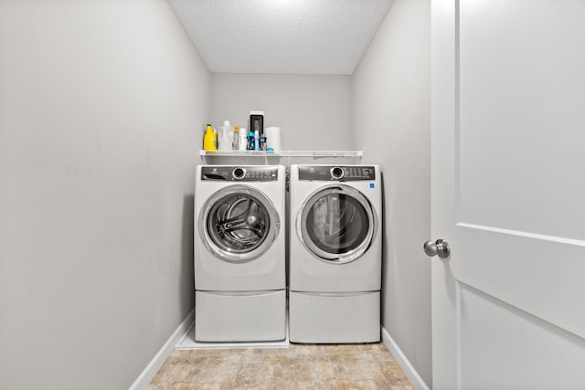 washroom with washing machine and clothes dryer, laundry area, a textured ceiling, and baseboards