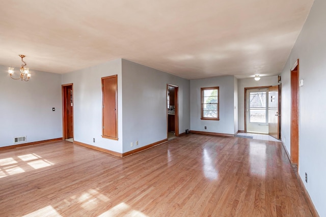 spare room with visible vents, baseboards, an inviting chandelier, and light wood-style flooring