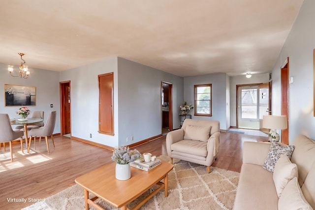 living area with light wood-style flooring, a notable chandelier, and baseboards