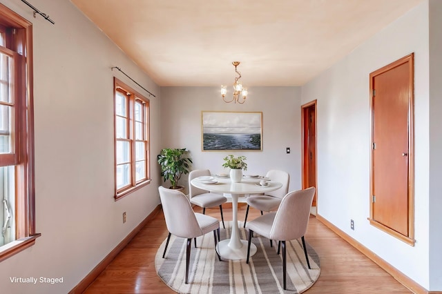 dining space with baseboards, light wood-style floors, and a chandelier