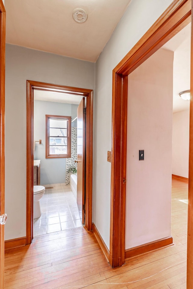 corridor featuring baseboards and light wood-style floors