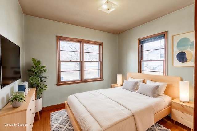 bedroom with baseboards, multiple windows, and wood finished floors