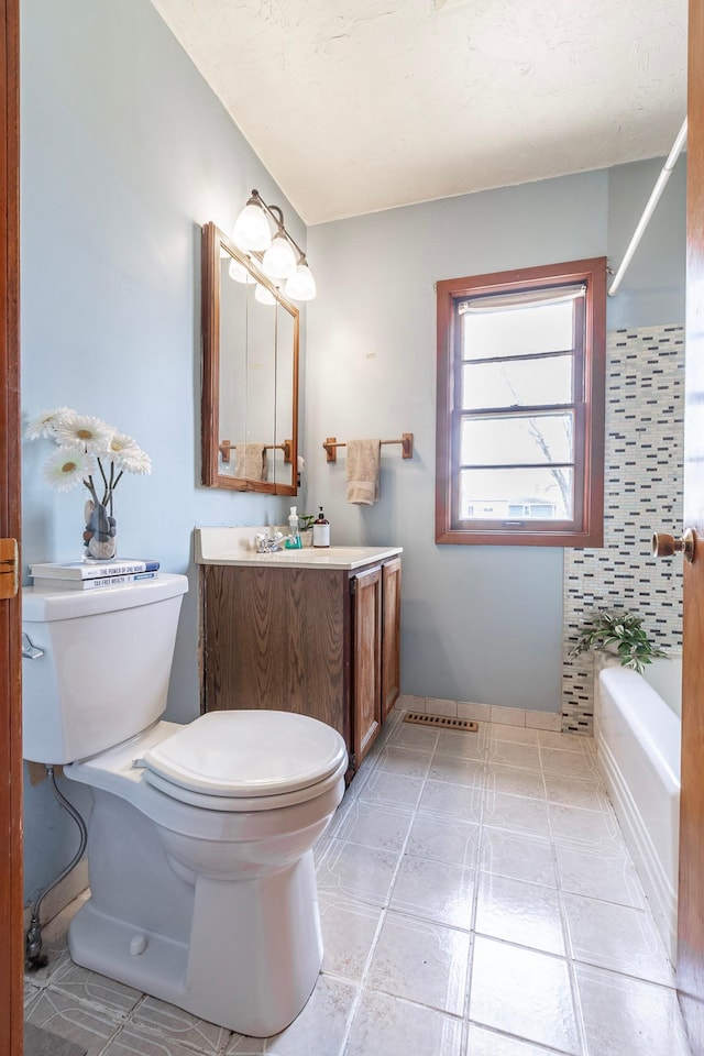 bathroom with a washtub, toilet, and vanity