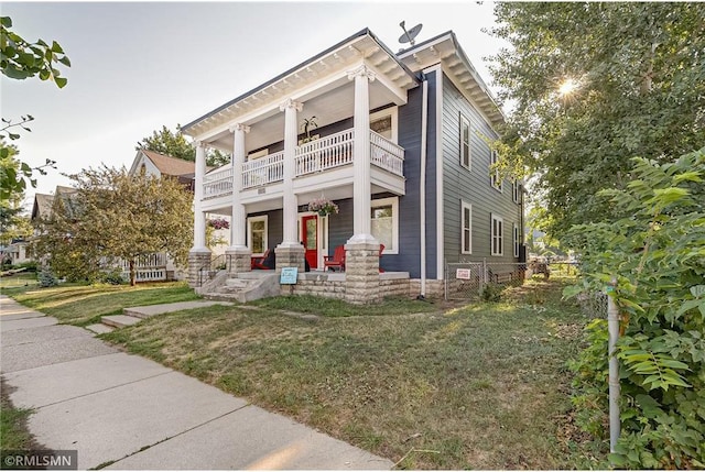 greek revival inspired property with a front lawn and a balcony