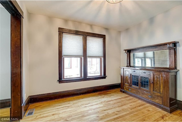 unfurnished living room with baseboards, visible vents, and light wood-type flooring