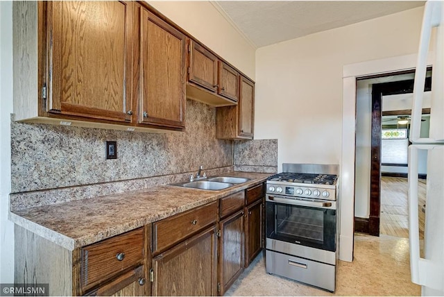 kitchen with a sink, backsplash, stainless steel range with gas stovetop, and brown cabinetry