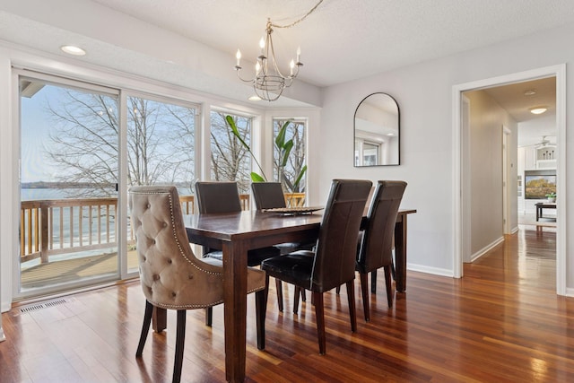 dining area with a notable chandelier, wood finished floors, baseboards, and a textured ceiling