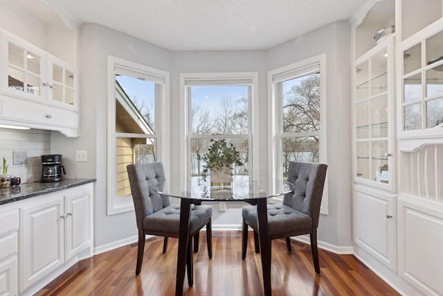 dining space with dark wood-style floors, a healthy amount of sunlight, and baseboards