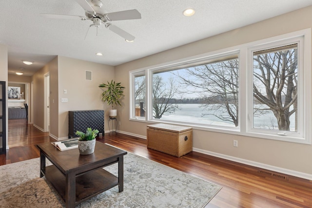 living room with visible vents, a textured ceiling, baseboards, and wood finished floors