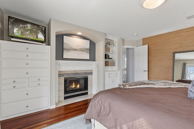 bedroom with a textured ceiling, wood finished floors, and a fireplace