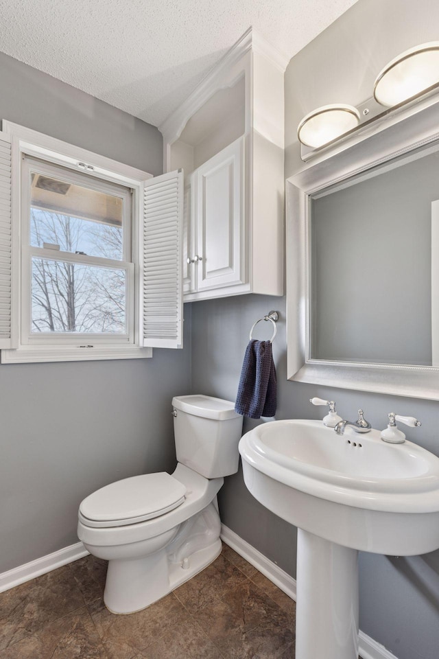 bathroom with baseboards, toilet, and a textured ceiling