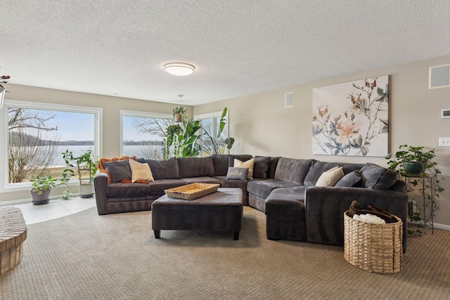 carpeted living area featuring tile patterned floors, visible vents, and a textured ceiling