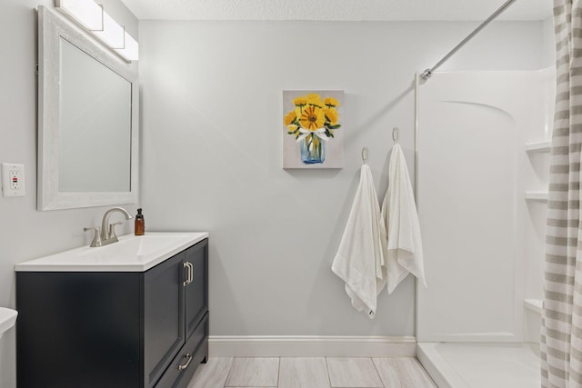 bathroom with curtained shower, a textured ceiling, vanity, and baseboards