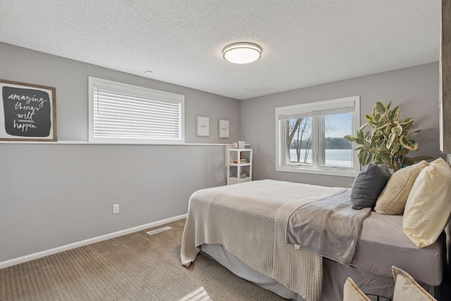 bedroom featuring baseboards, carpet floors, a textured ceiling, and visible vents