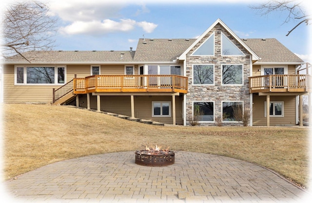 back of property featuring a fire pit, a yard, a deck, a patio area, and stone siding