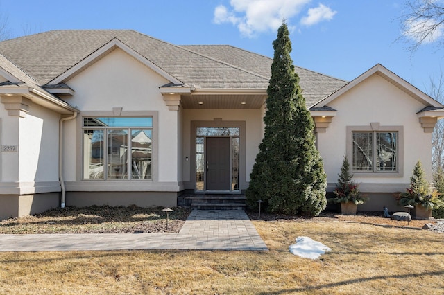 view of front of house with stucco siding and roof with shingles