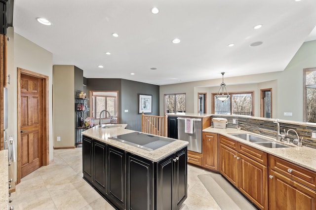 kitchen featuring a sink, stainless steel dishwasher, an island with sink, and electric stovetop