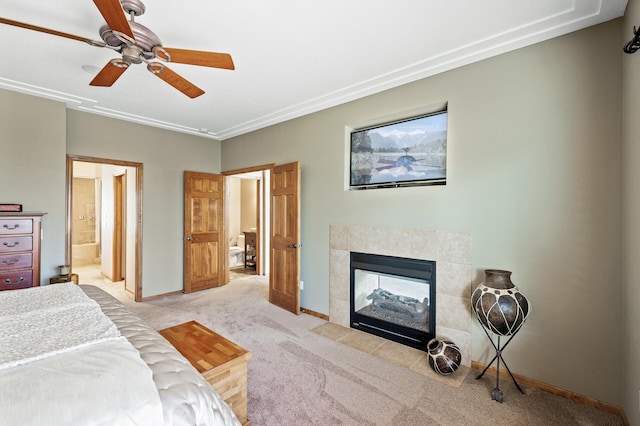 bedroom with baseboards, ceiling fan, a tile fireplace, light carpet, and connected bathroom