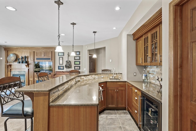 kitchen featuring a kitchen bar, brown cabinetry, beverage cooler, and a sink