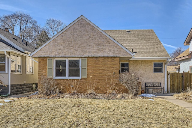 view of home's exterior with roof with shingles and fence