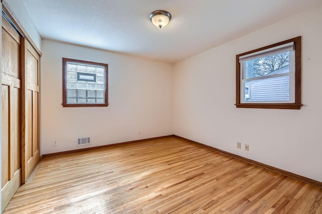 unfurnished bedroom featuring visible vents, light wood-type flooring, and baseboards